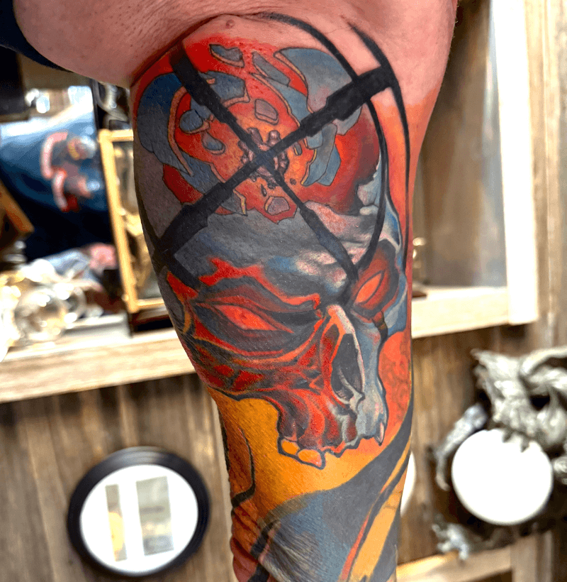 Vibrant color skull tattoo with mechanical and abstract design elements on the bicep, created at Bullett’s Ink in Mount Airy, Maryland.