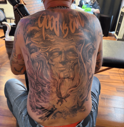 Full back tattoo featuring a dramatic “Good vs Evil” design with detailed faces and flowing imagery, created at Bullett’s Ink in Mount Airy, Maryland.