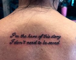 Elegant script tattoo with a meaningful quote on the upper back.